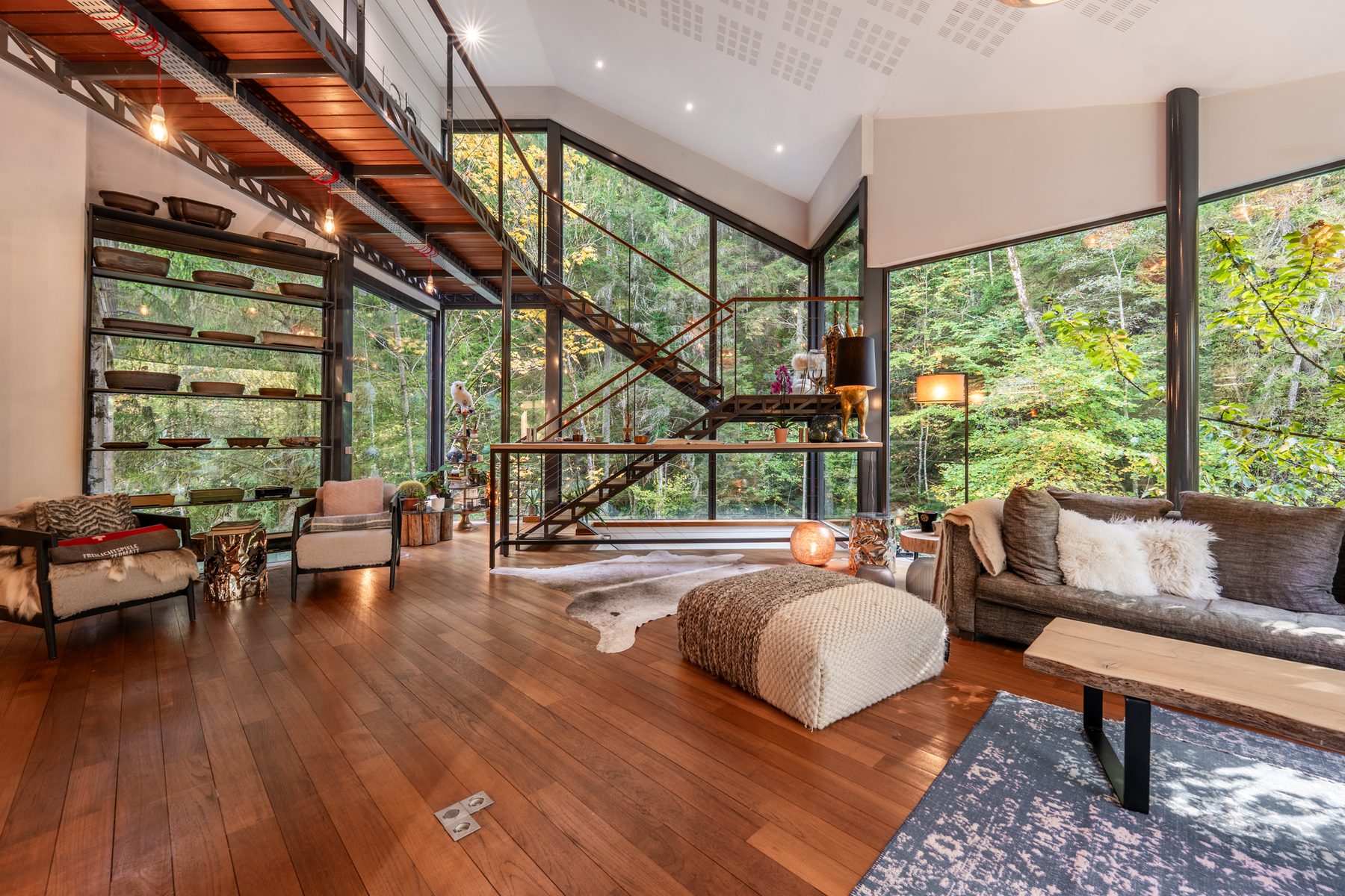 Double séjour avec mezzanine, escalier suspendu et grandes verrières sur la forêt