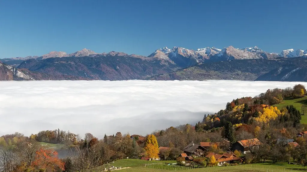 Mer de nuages à l'automne avec vue sur les sommets enneigés et chalets en couleurs