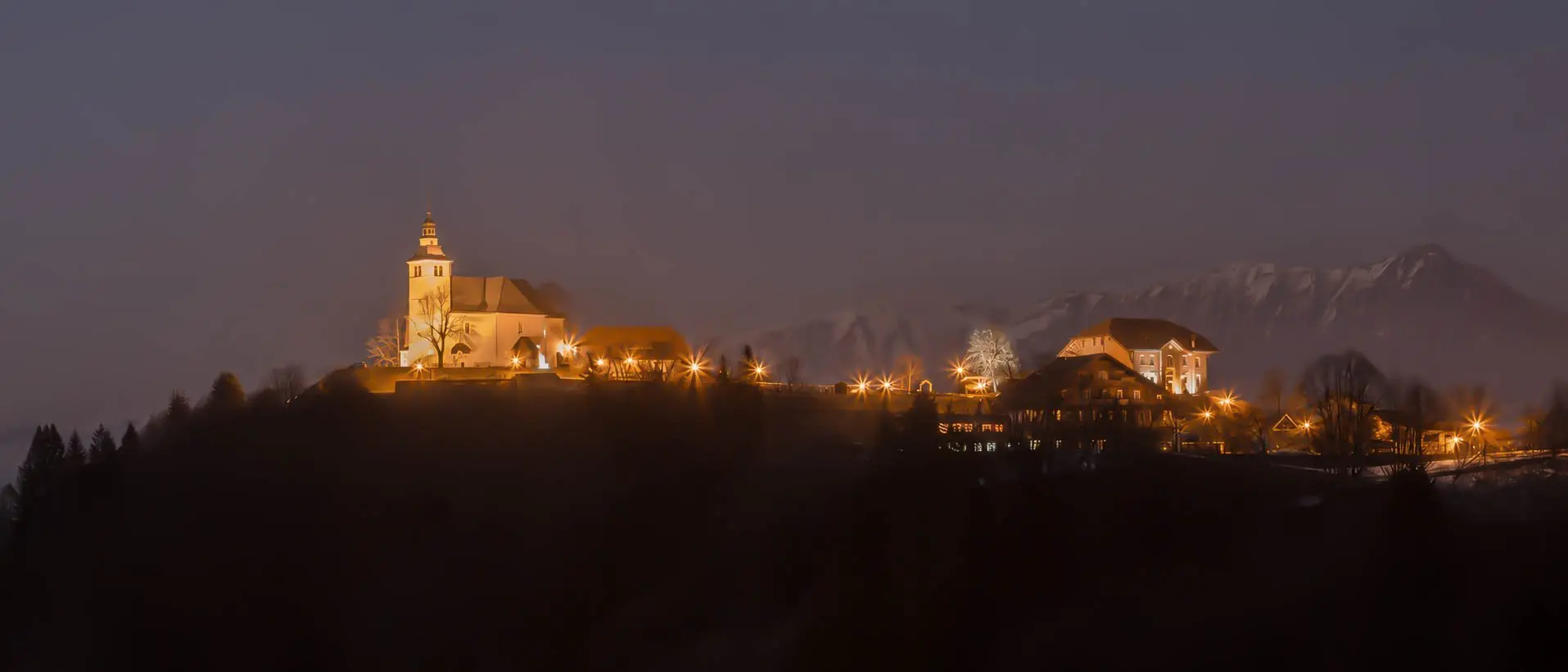 Mont-Saxonnex à la nuit tombée, l'église et le hameau illuminés face aux sommets enneigés du Bargy